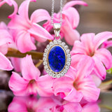 An Oval Blue Australian Opal with a rubover setting of 18ct Yellow Gold and surrounded with a cluster of 0.55ct Diamonds, set in 18ct White Gold and dangling on a 18ct White Gold Chain.